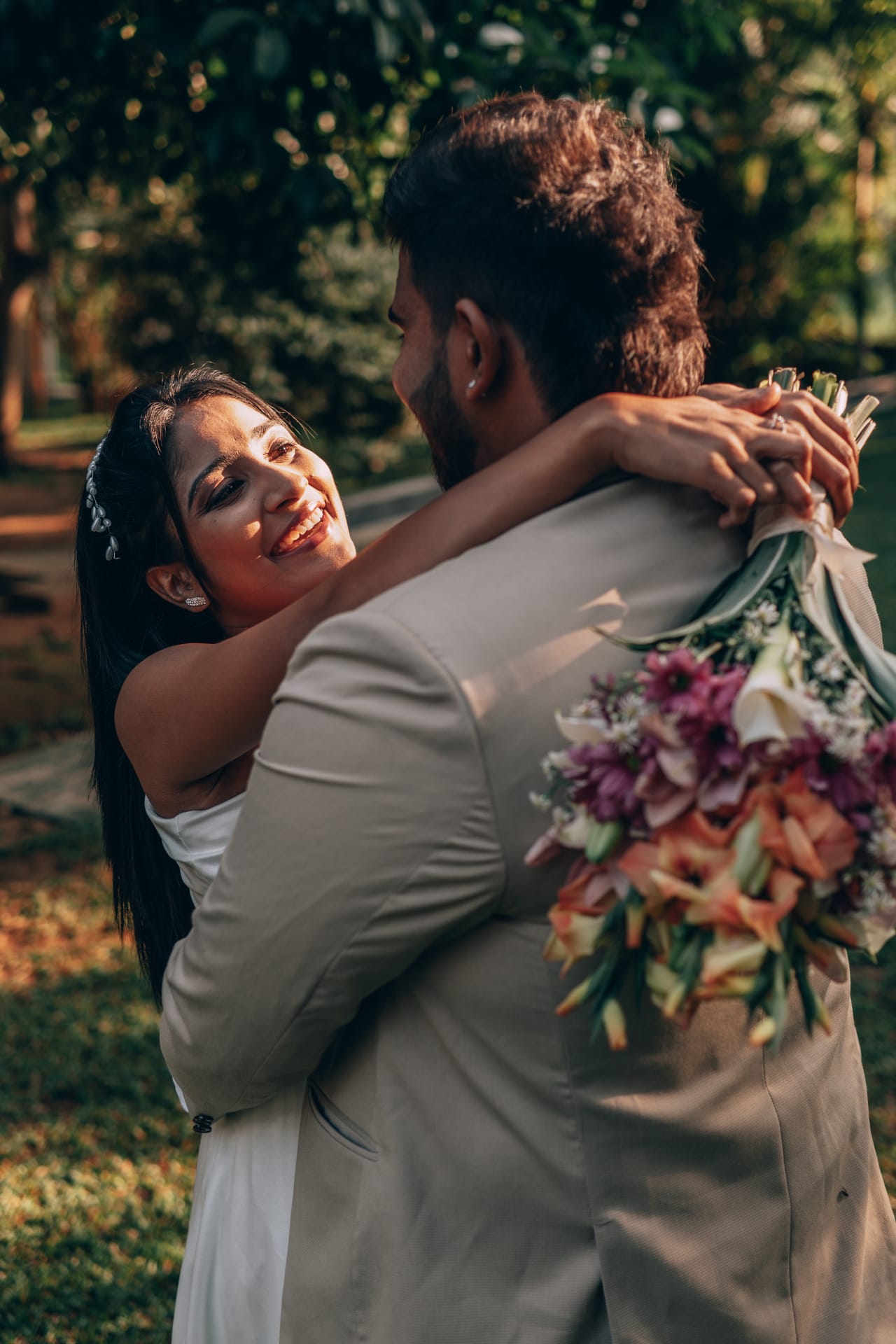 A bride resting on her groom's shoulder, her bouquet raised behind him