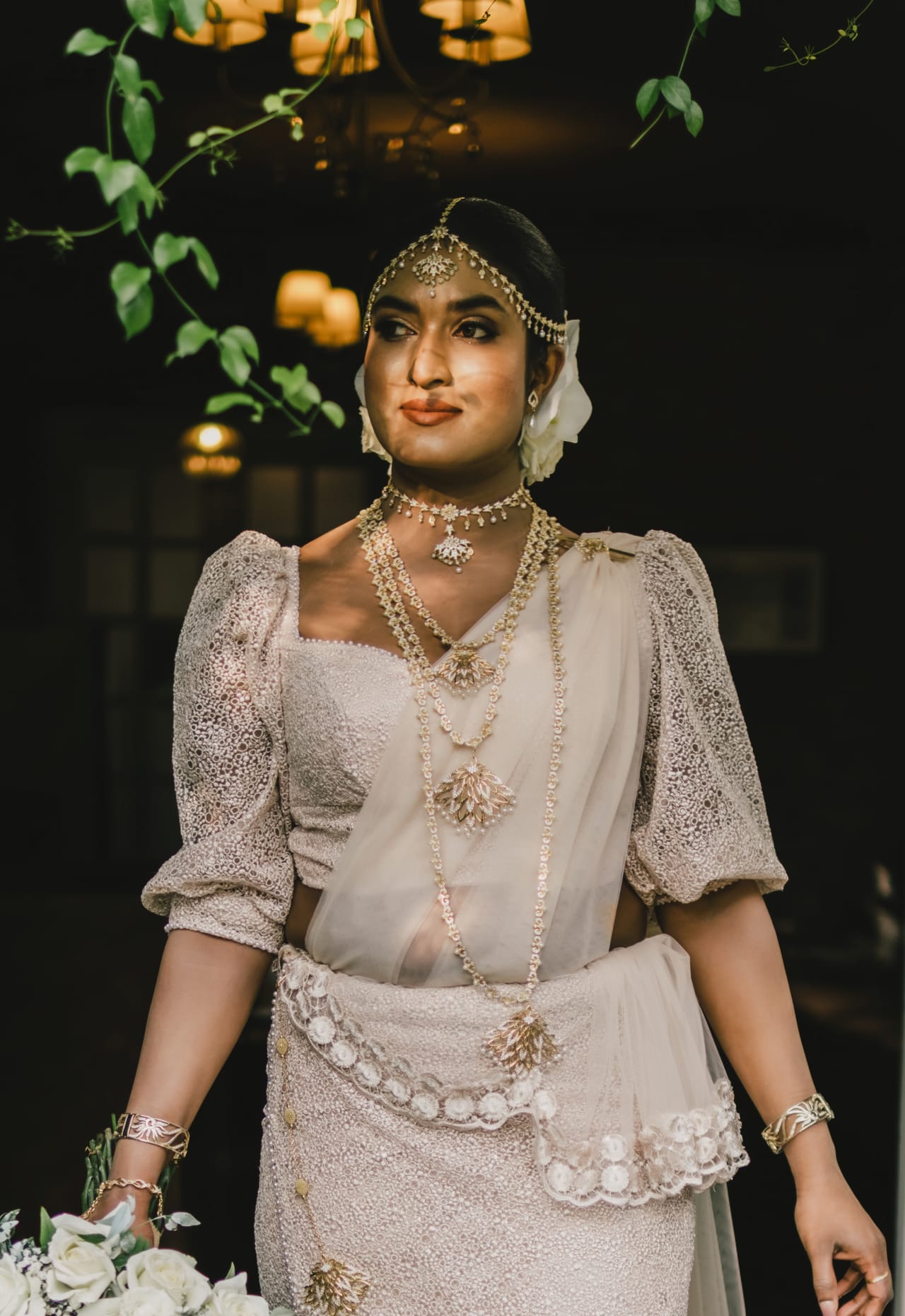 A Kandyan bride in traditional jewellery and headpiece against a dark background