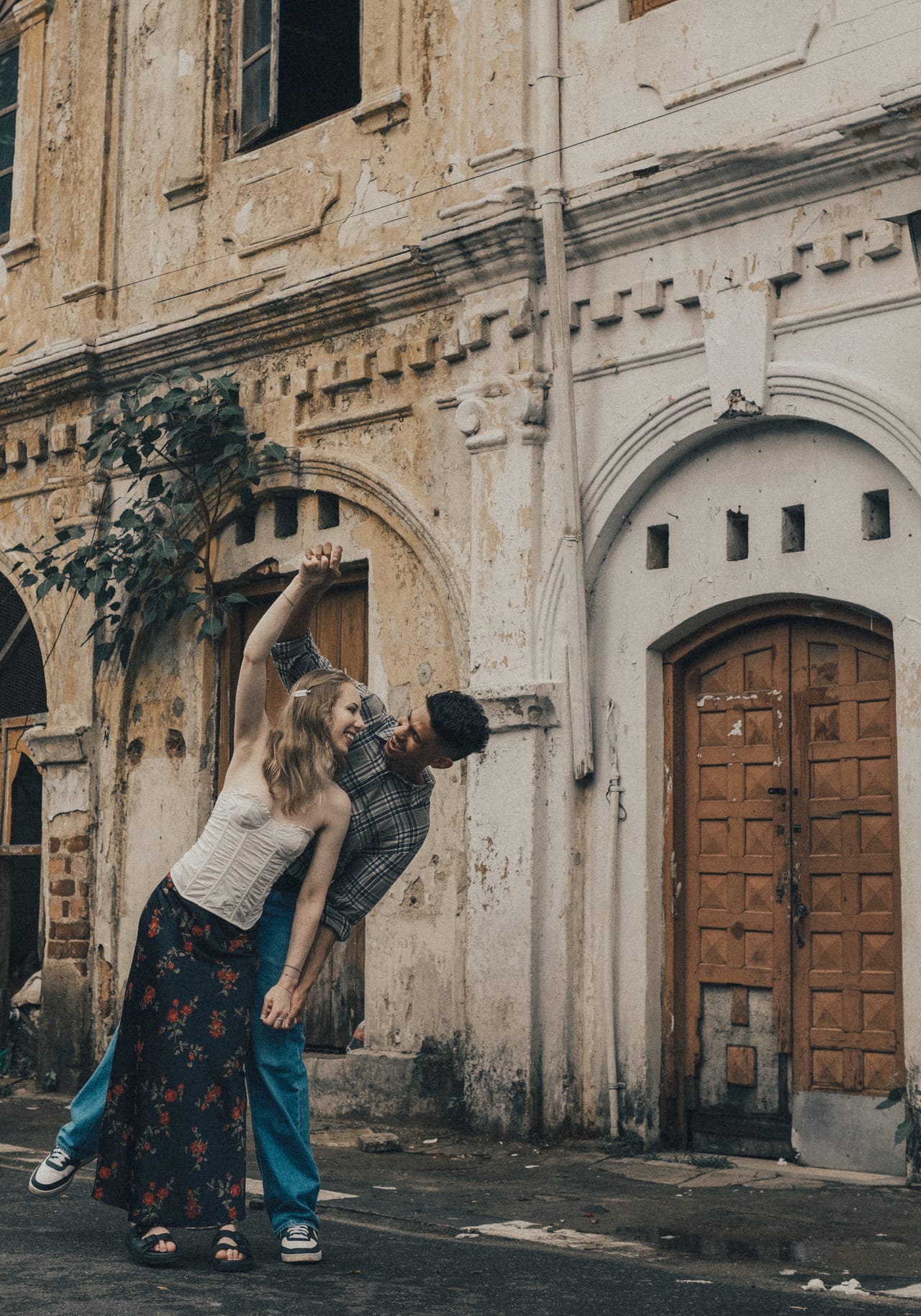 A couple playing in front of a crumbling colonial archway