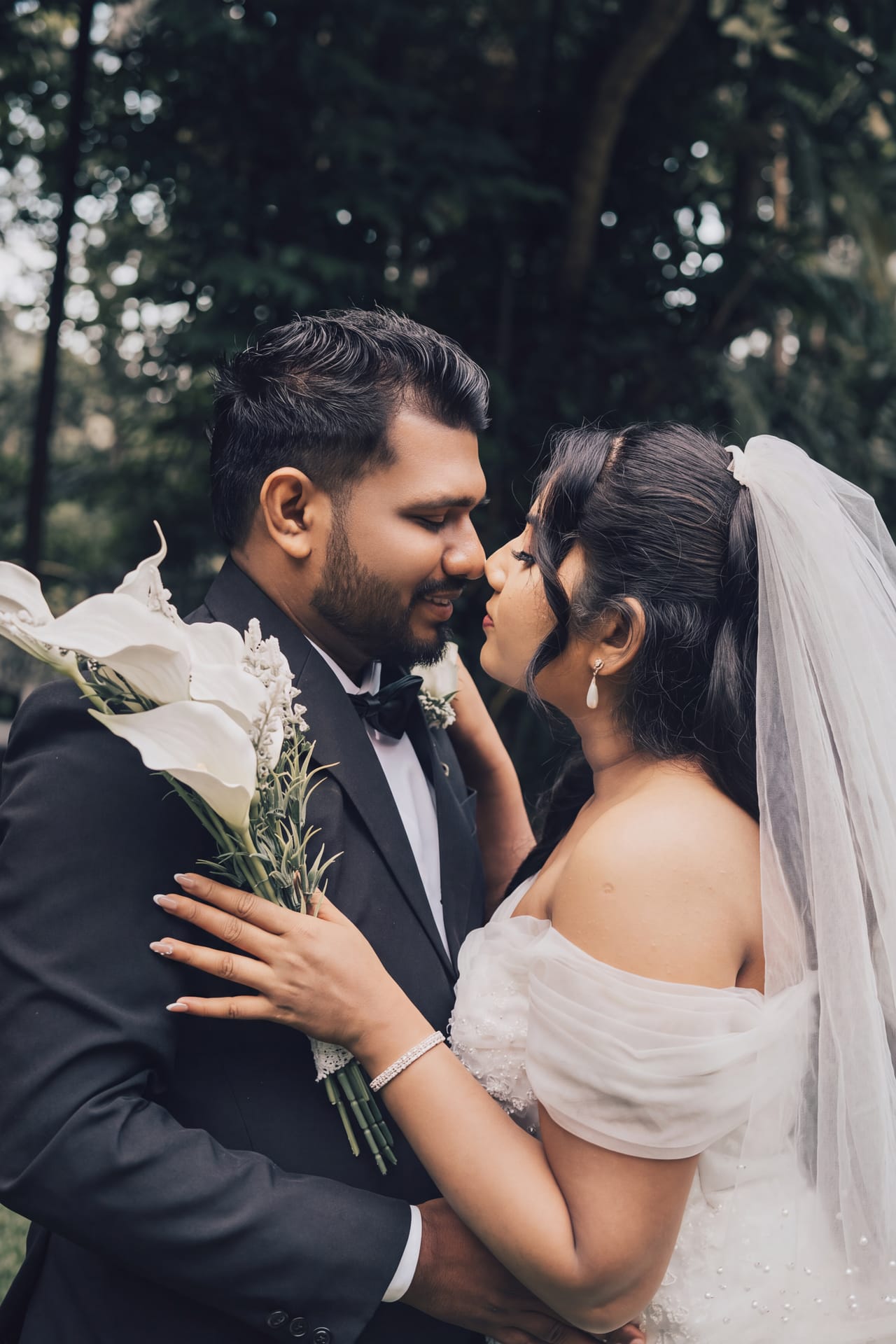 A bride and groom resting their foreheads together beneath her veil